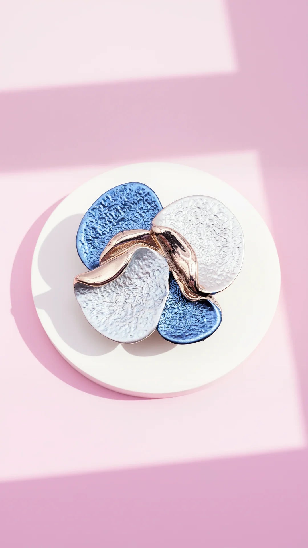 colorful brooch displayed on a white surface against a pink background