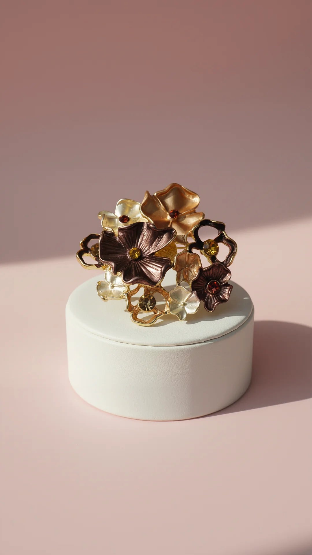 Decorative brooch with floral design on a white base against a pink background