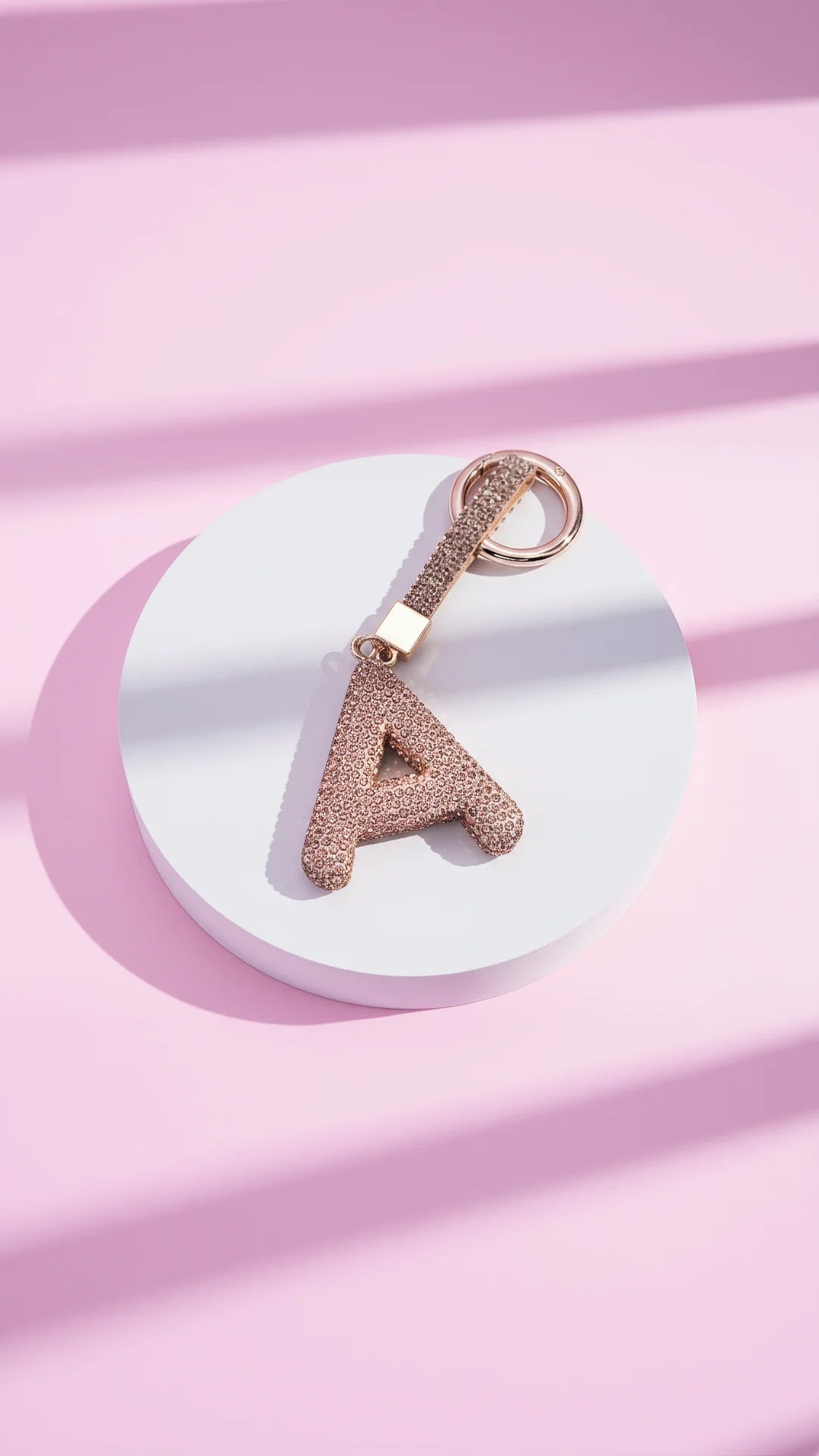 Rose gold keychain with letter 'A' on a pink fabric background