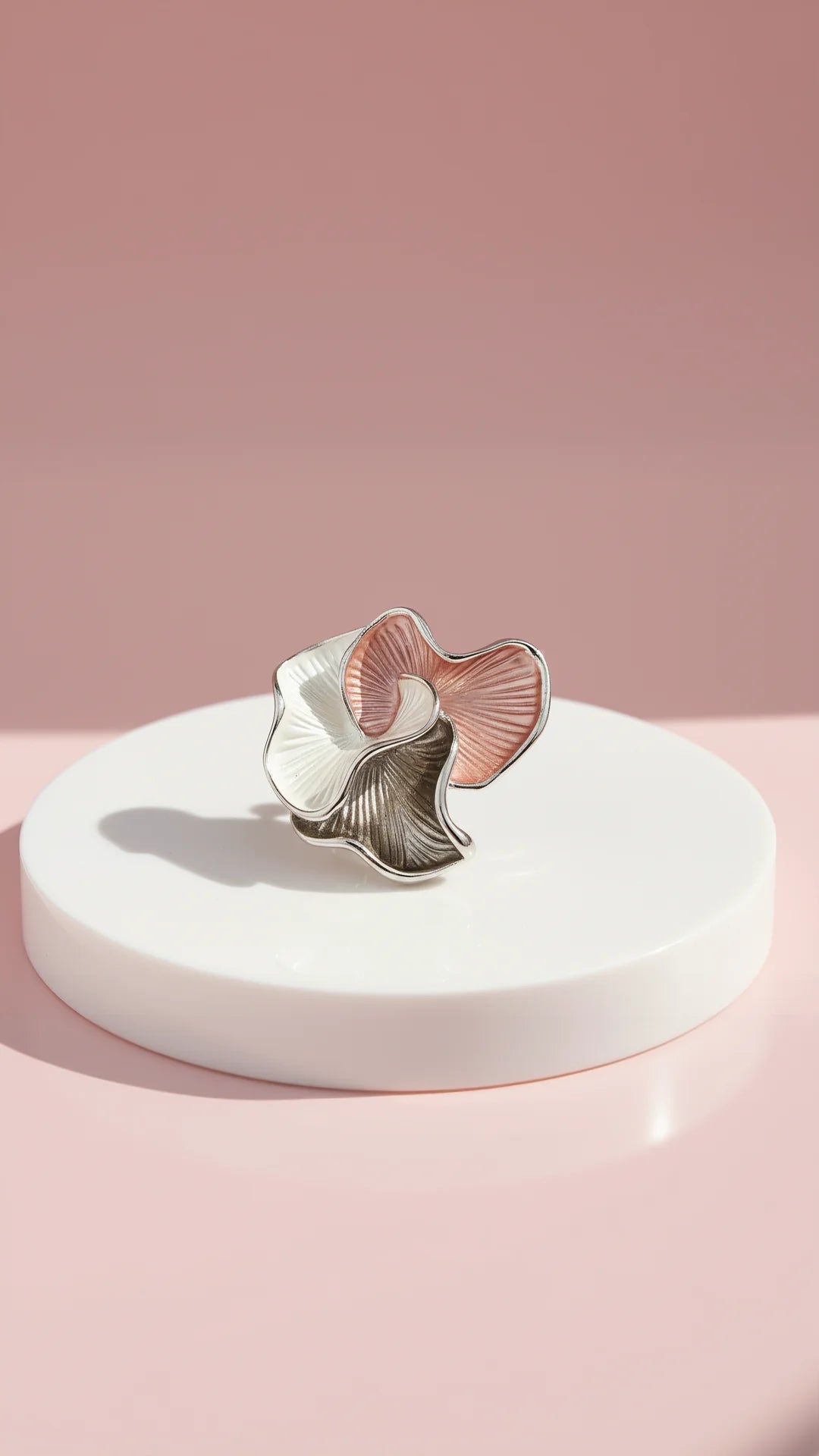 Decorative brooch ornament on a white stand against a pink background
