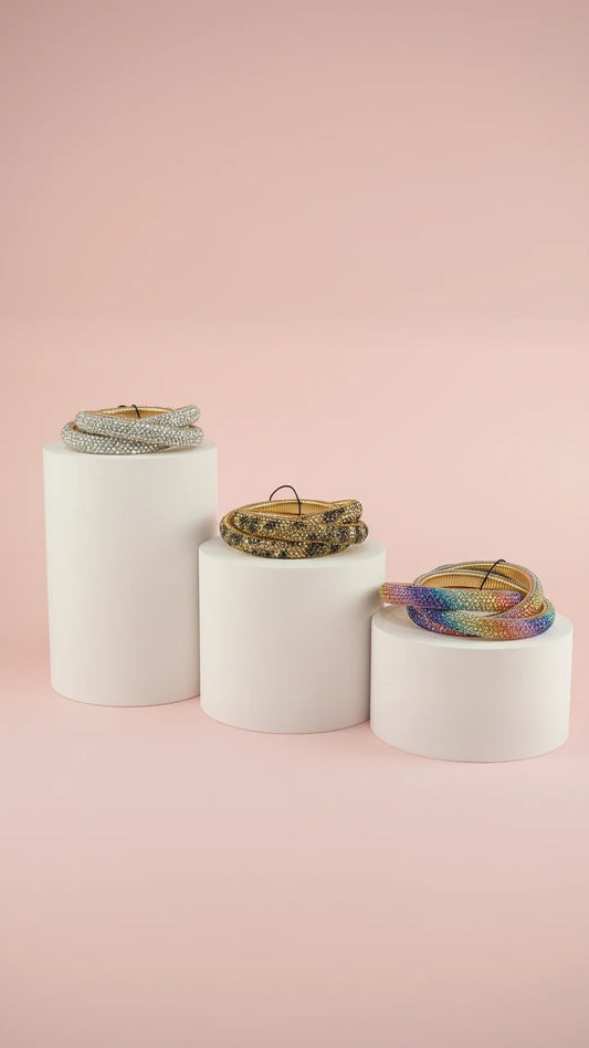 Three cylindrical white containers with bracelets on a pink background