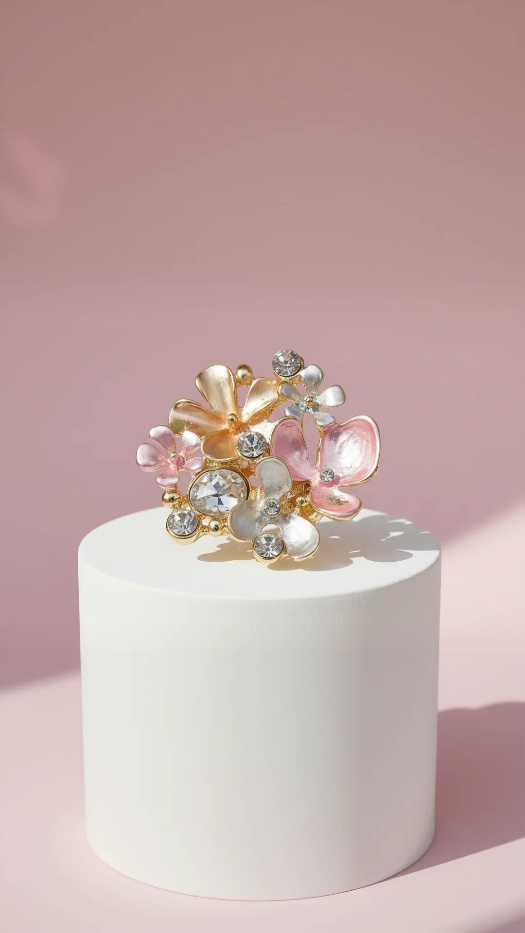 Decorative brooch with floral and gemstone design on a white pedestal against a pink background