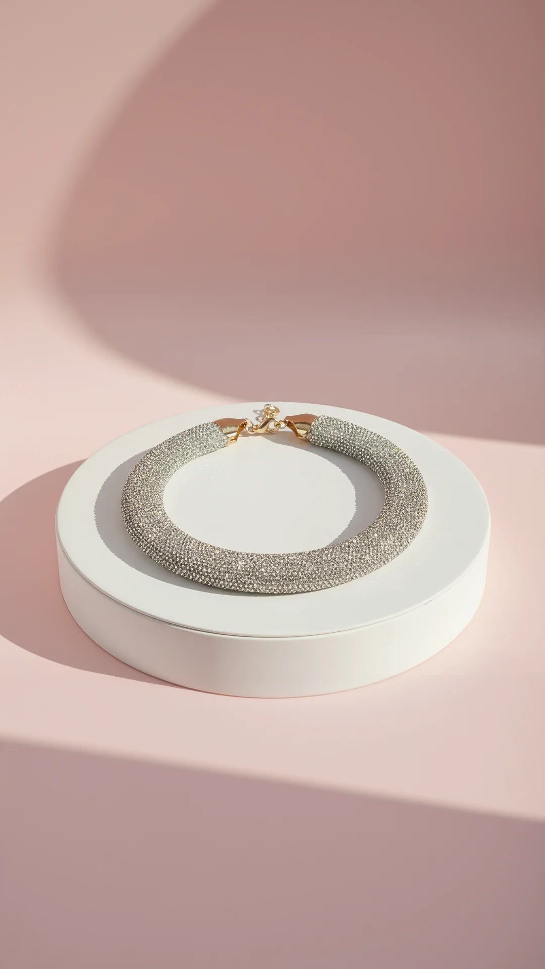 Necklace on a white stand with a pink background
