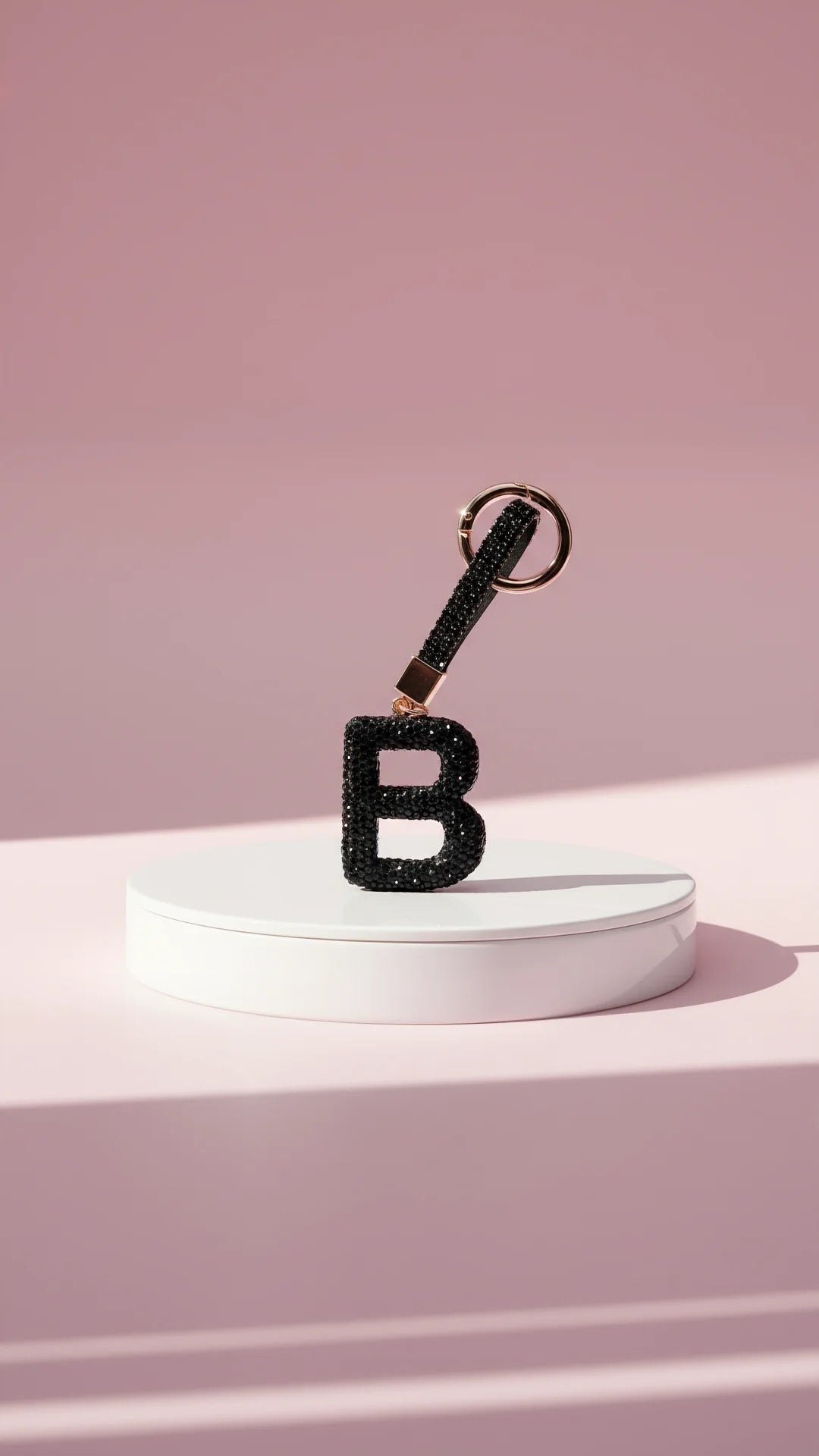 Black letter 'B' keychain with glittery texture on a pink background