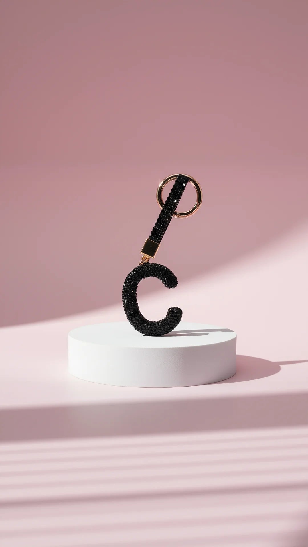 Black letter 'C' keychain with glittery texture on a pink background