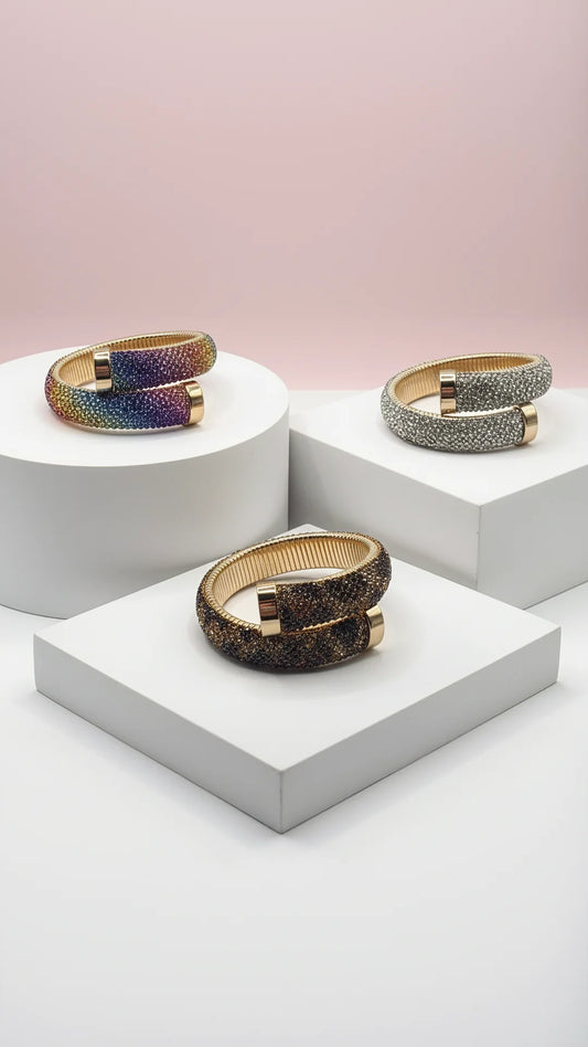 Three cuffs with brown, silver and multicolor colors displayed on white surfaces against a light pink background