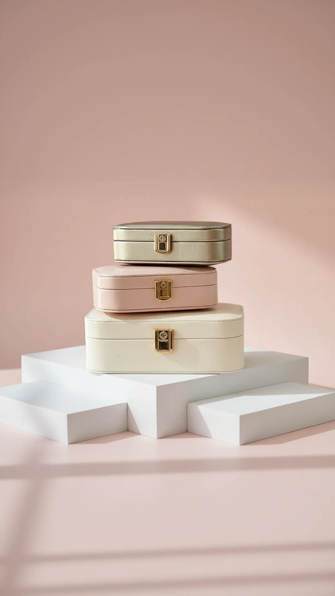 Three different sizes of jewellery box in 3 different colors, displayed on a white surface against a pink background
