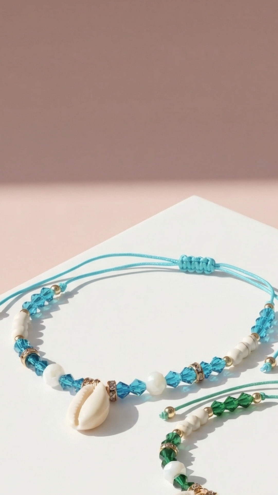 Anklets with blue beads and cowrie shells on a pink background