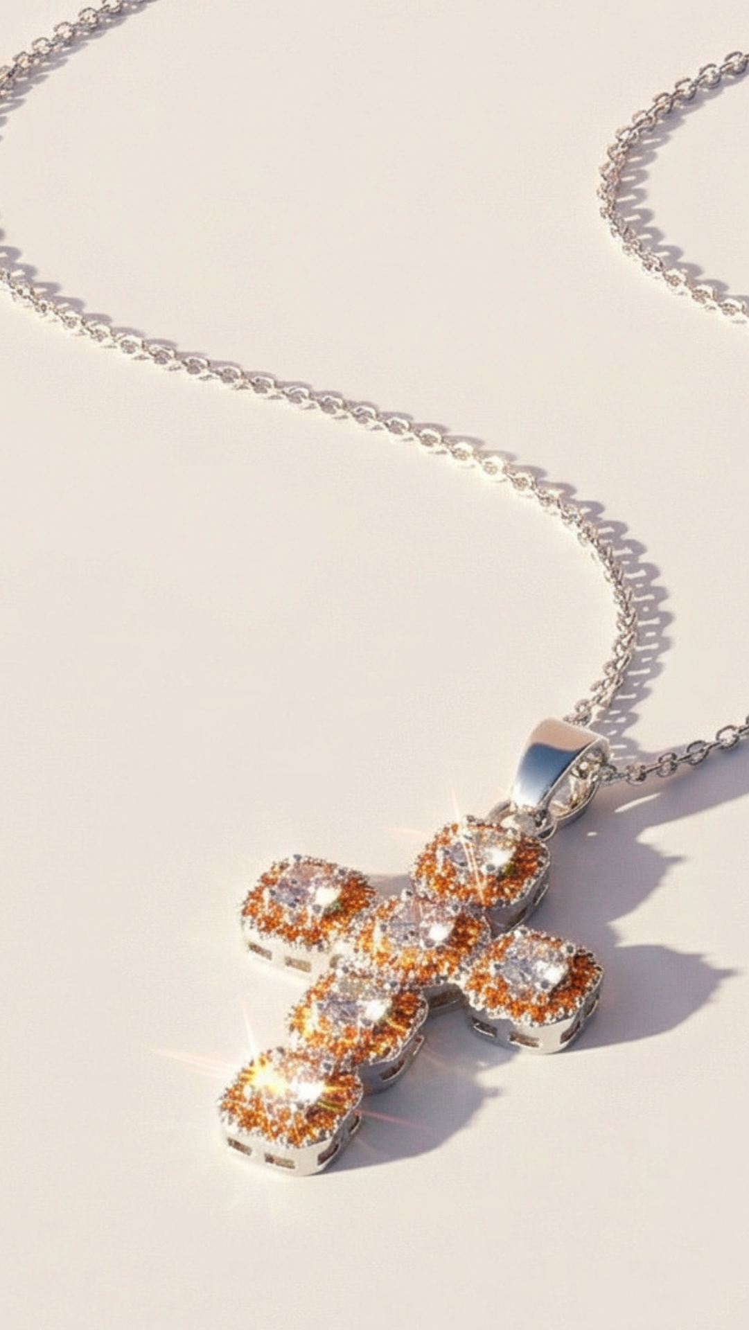 Clear crystal cross pendant with a mix of golden and silver finish, displayed on a white surface
