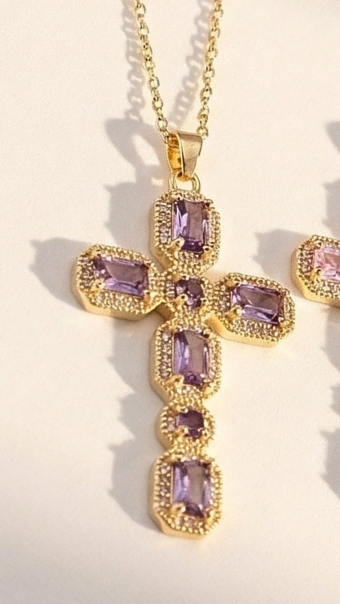 Gold necklace with purple gemstones on a light background