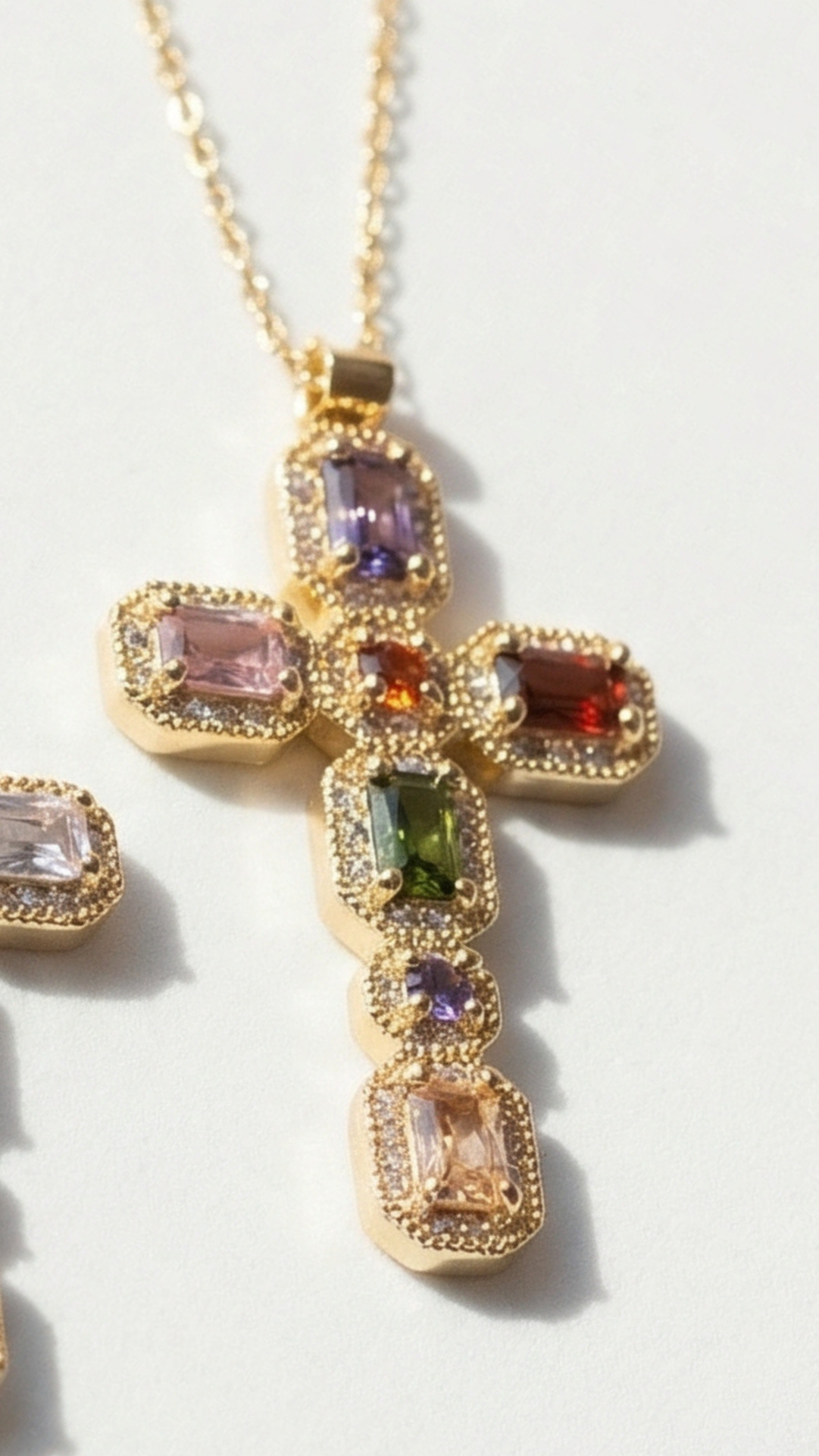 Multicolor gemstone cross pendant with golden finish displayed on a white surface