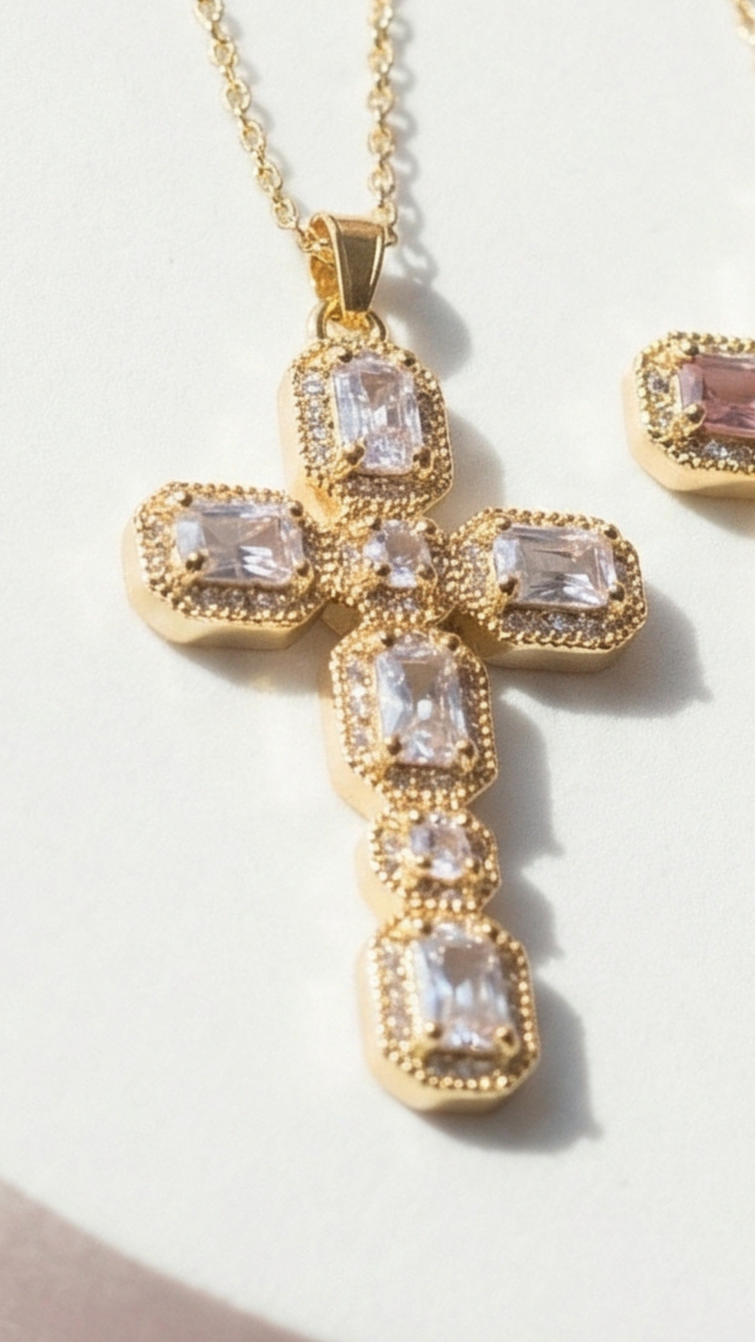 Gold cross pendant with clear stones on a light background