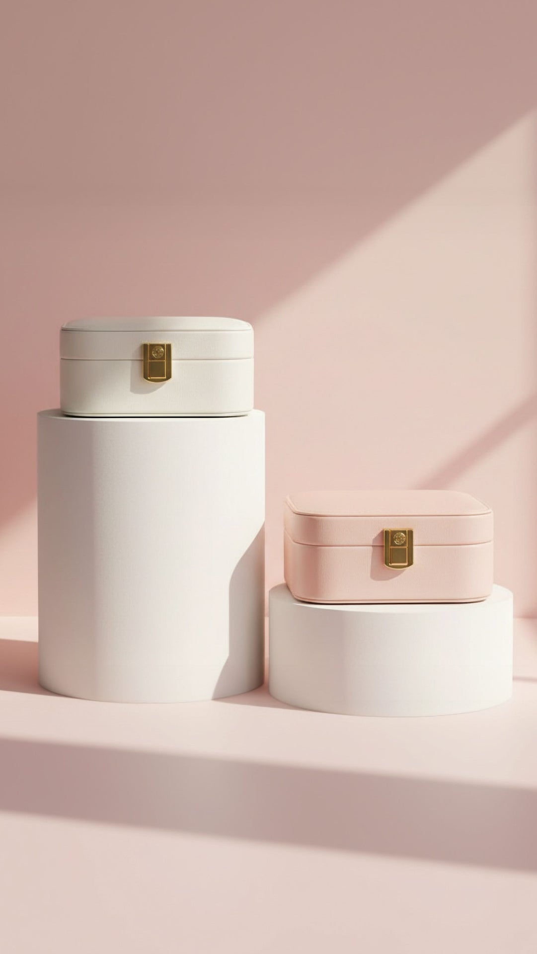 Two round, white and pink jewelry boxes with gold accents on a pink background