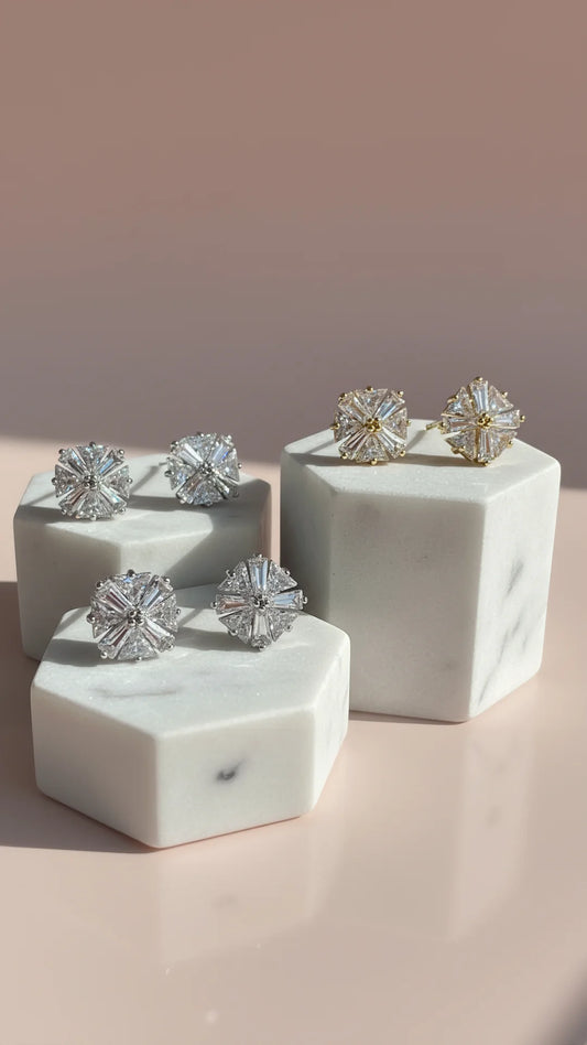 Set of crystals earrings on marble stands against a pink background