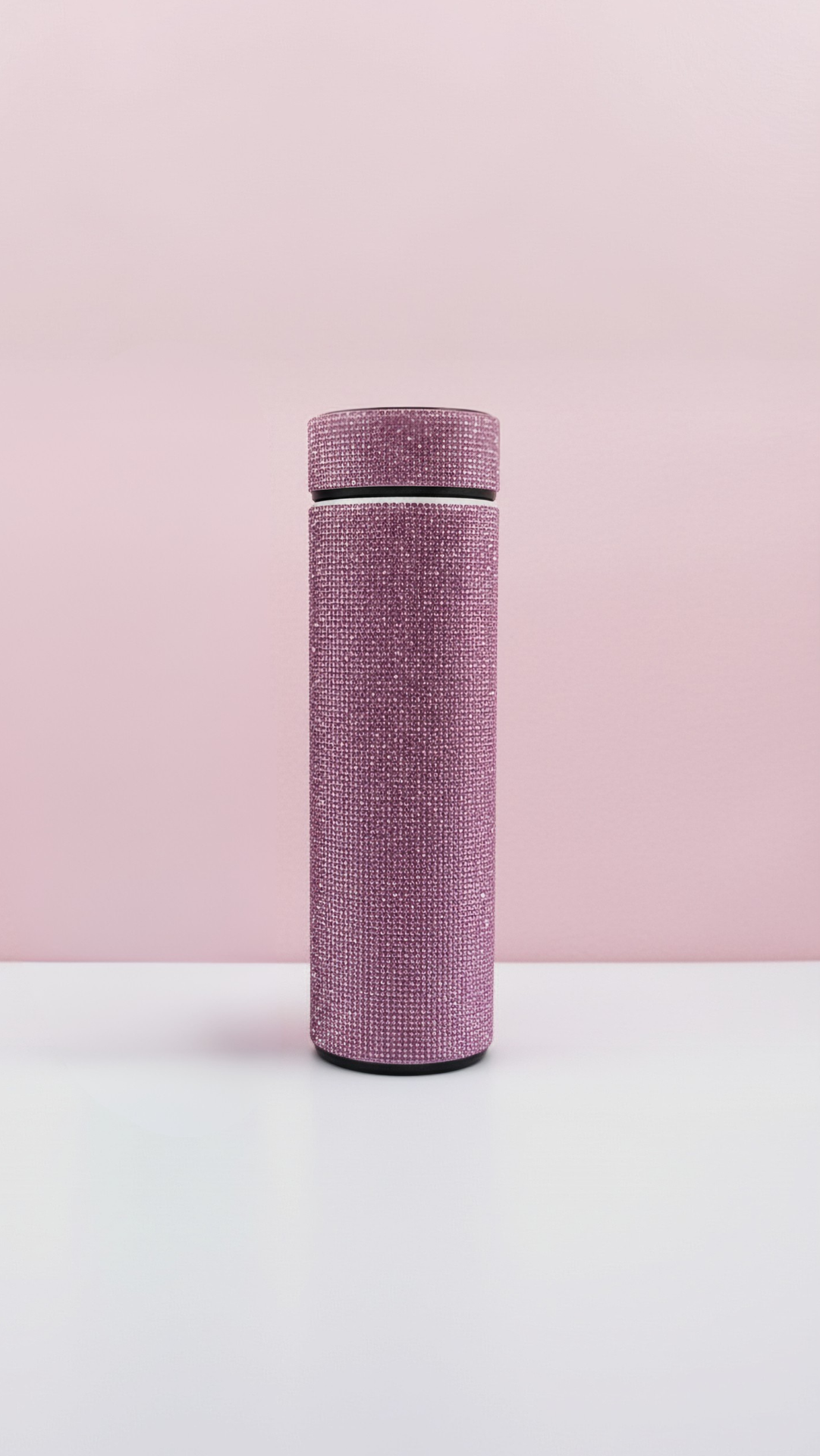 Pink bottle displayed on a white surface against a pink background