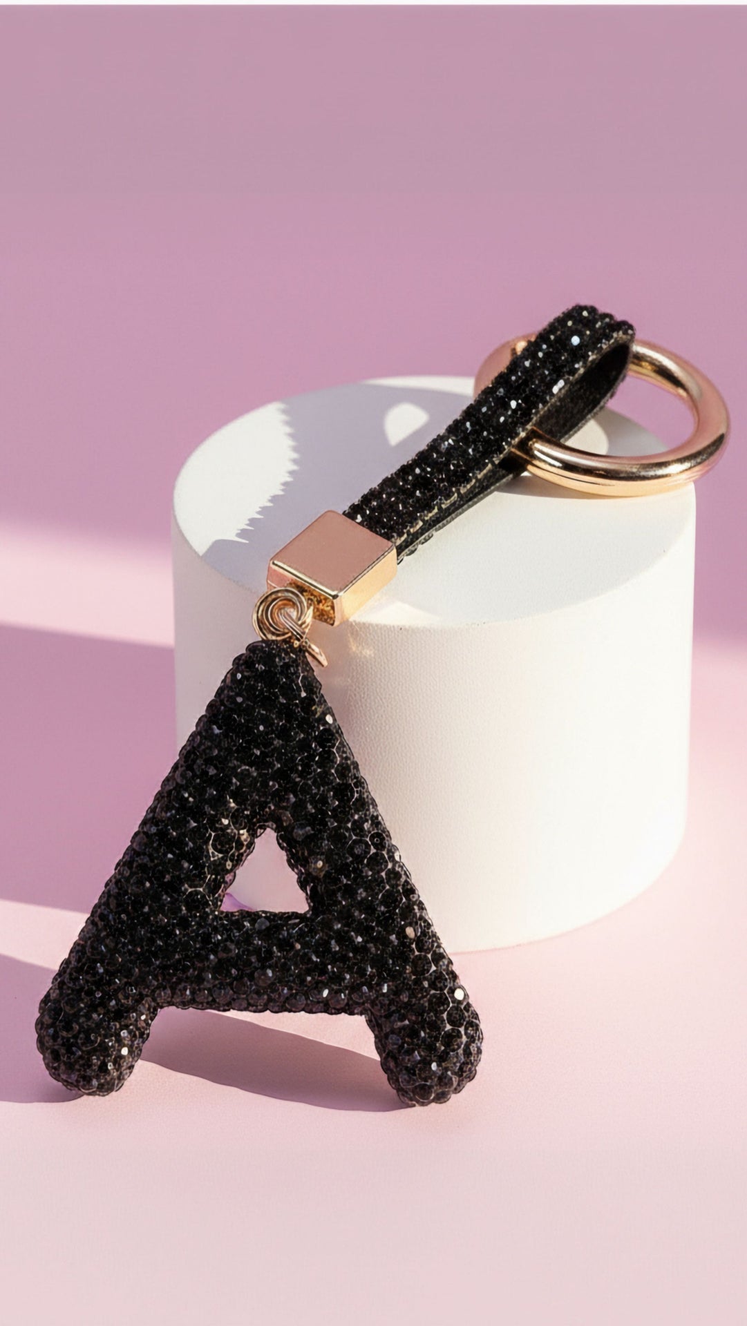 Black letter 'A' keychain with glittery texture on a pink background