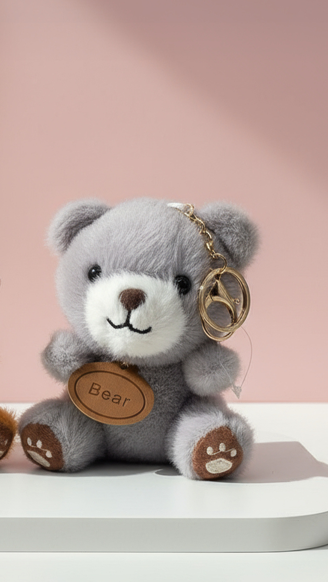 Gray teddy bear keychain with a pick background