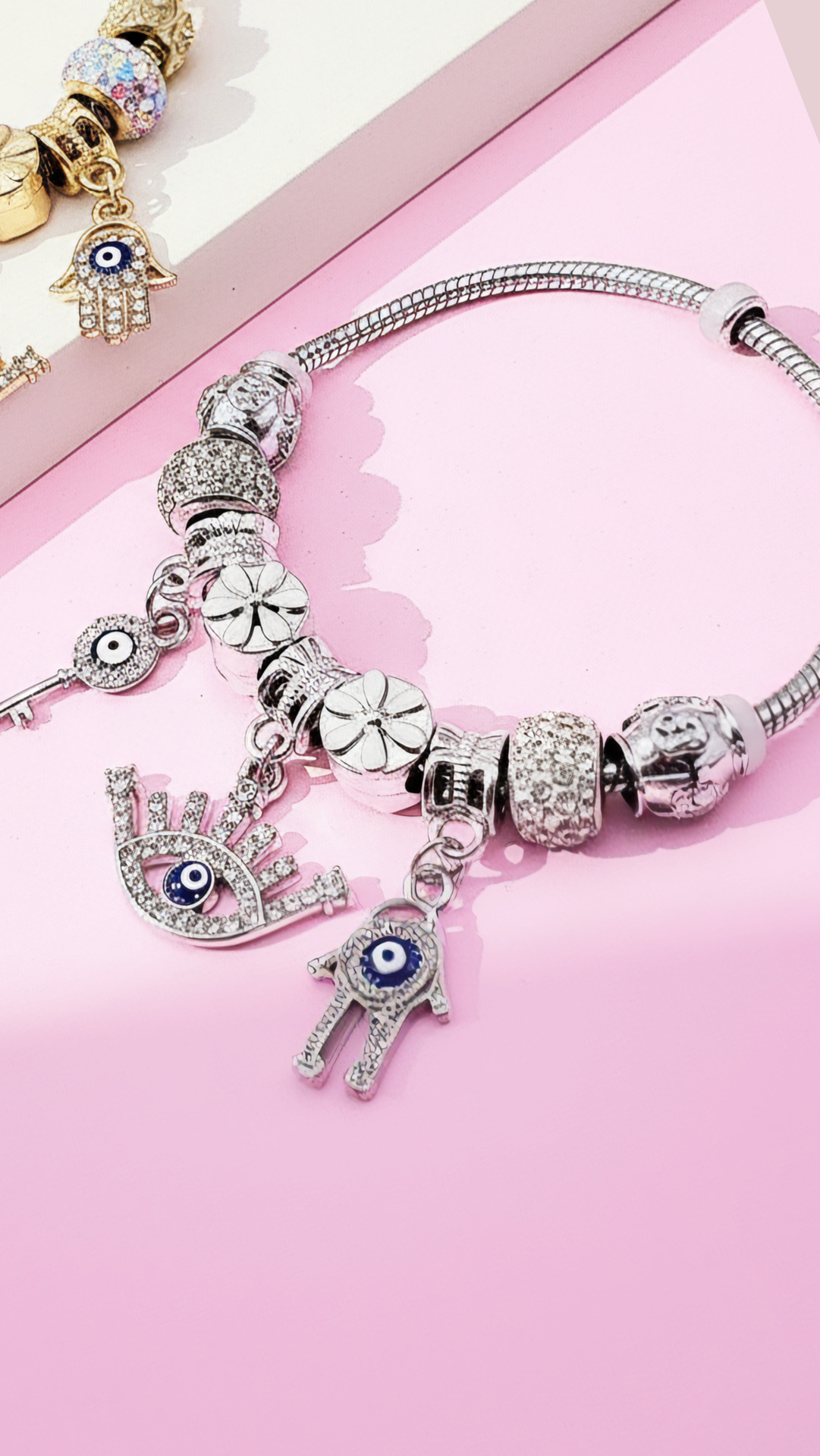 Silver bracelet with charms displayed against a pink background