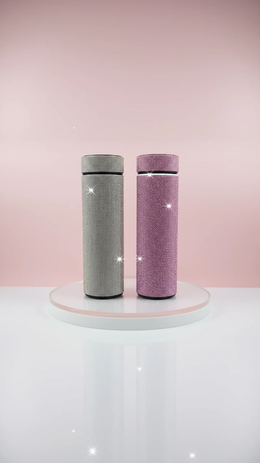 Two cups in silver and pink colors displayed against a pink background
